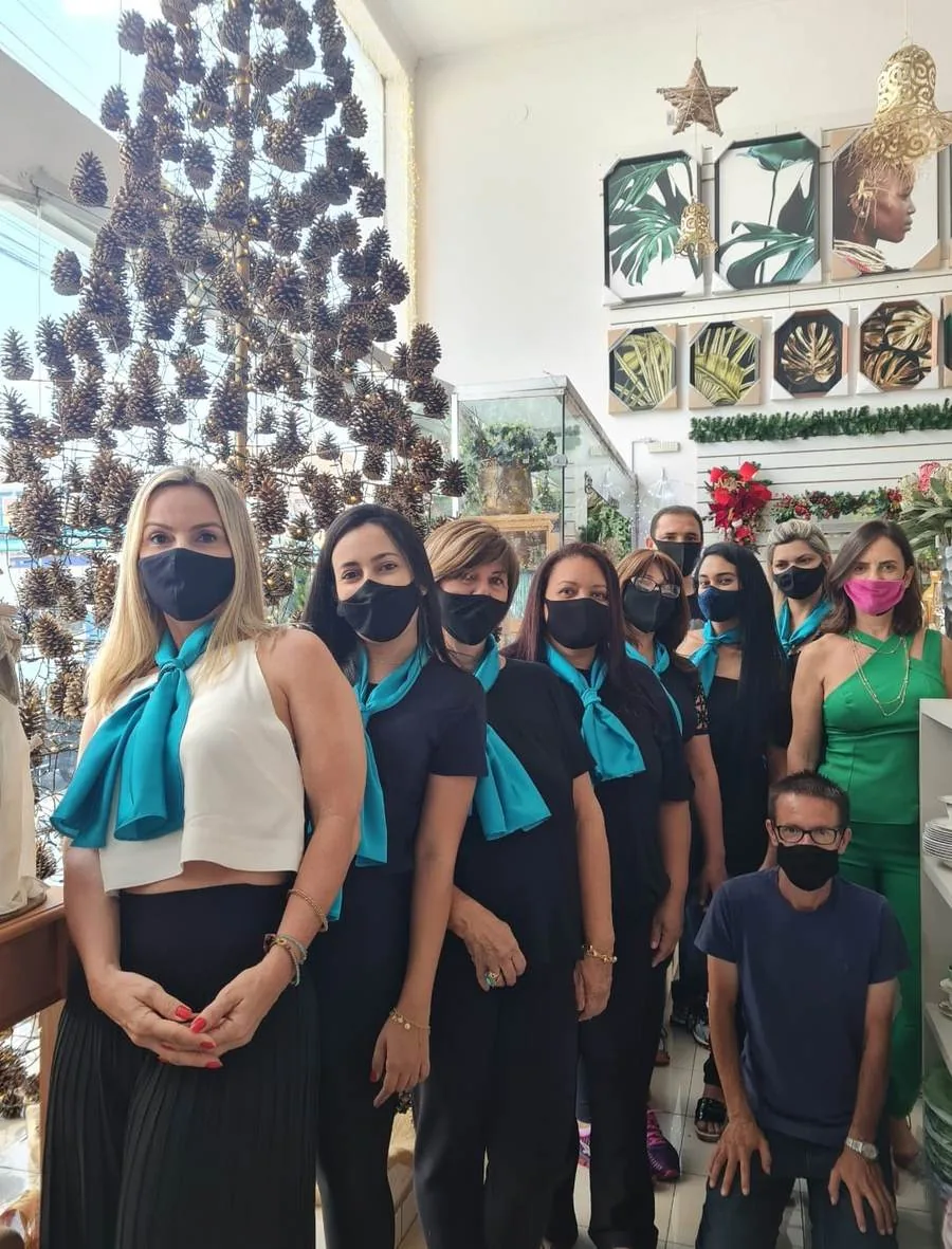A equipe da loja de máscara, posando diante da árvore de pinhas montada no vão central